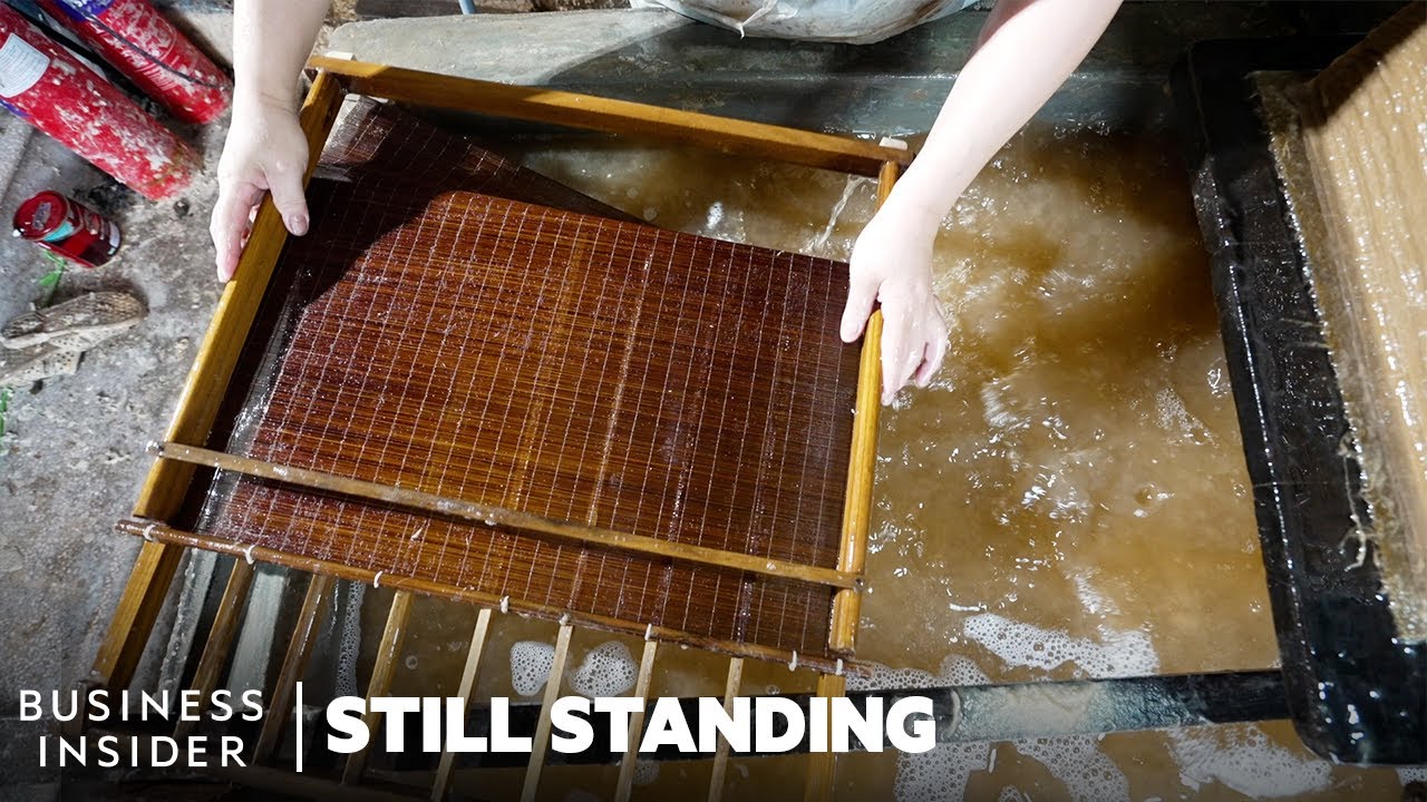 An artisan forming a sheet of Dó paper by hand on a bamboo screen